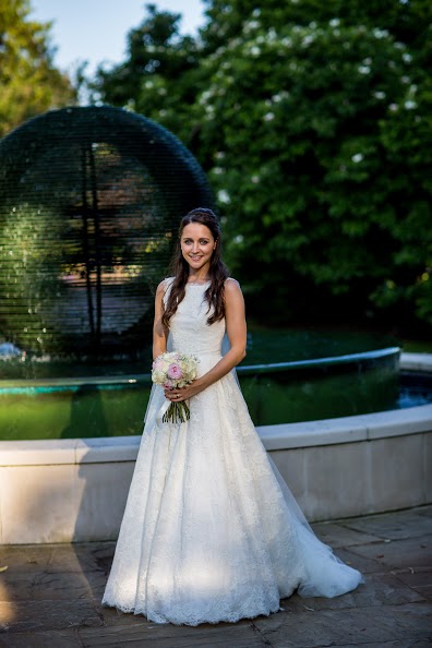 London bride stood by a fountain in hair and makeup.