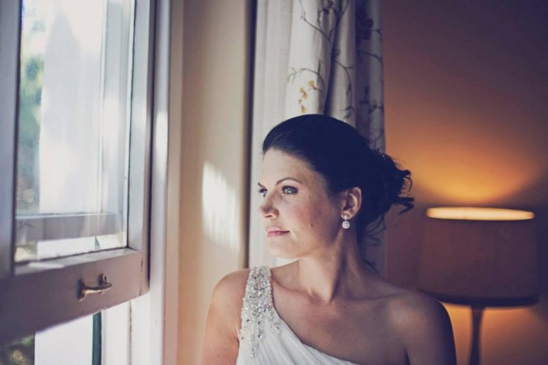 London Bride looking out of window in hair and makeup.